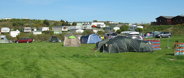 tents on a gren field with static campervans on the hillside